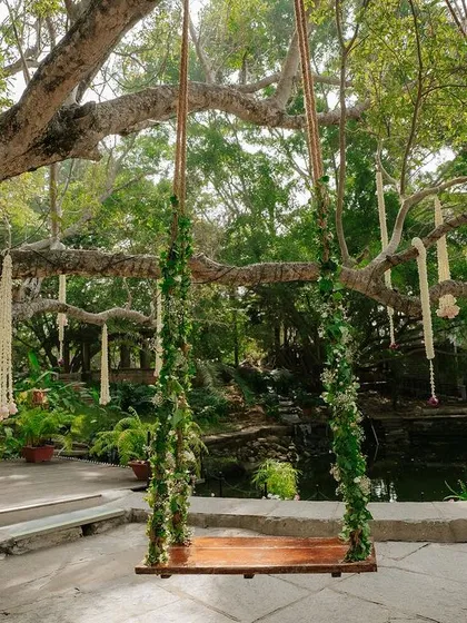 A swing decorated with lush green foliage, a simple, elegant, and nature-inspired decor choice.