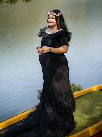 Our black off-the-shoulder mermaid gown is a client favorite. It offers a timeless, elegant look that beautifully accentuates the baby bump, perfect for both studio and outdoor settings.