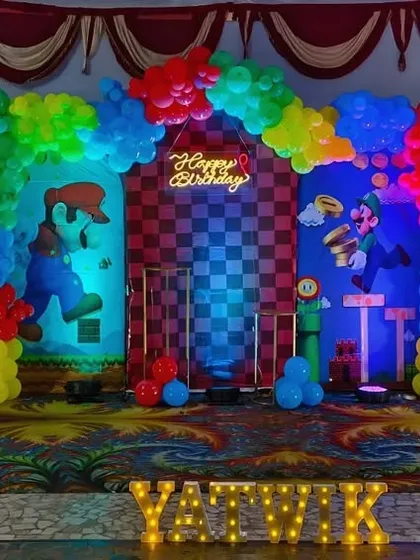 Level up your party with a Super Mario themed birthday decoration. This setup features colorful balloons representing the game's blocks, character cutouts, and multiple backdrops to create an immersive experience.