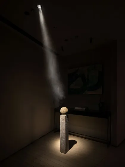 A single, powerful beam of light acts as a sculptural element itself, illuminating a stone artifact on a plinth. This demonstrates our belief that great design is not just seen, but felt.