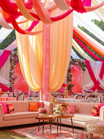 Haldi ceremonies are all about vibrant joy. I used a playful palette of pink, peach, and orange, with flowing drapes and cozy lounge seating, to design a space that felt like celebrating under a bright, happy sunset.