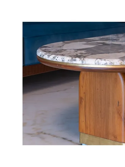 A close-up of the classic coffee table, showing the detail of the marble top and sculptural wooden leg.