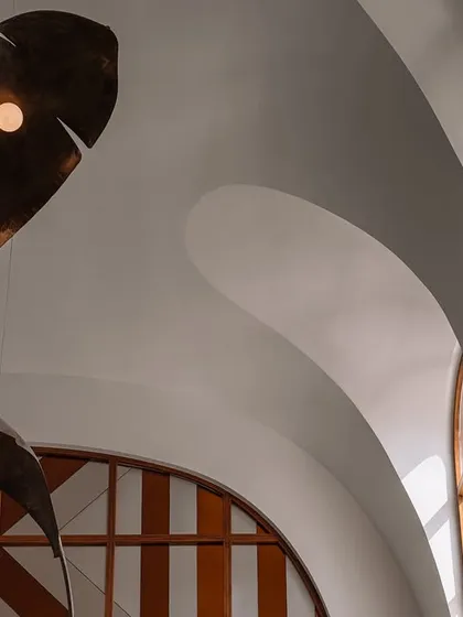 Lighting can be the jewelry of a space. In this double-height living room, we collaborated with artists to create this dramatic installation of oversized, illuminated metal fronds. The piece fills the grotto-inspired ceiling, casting a warm glow and acting as a magnificent sculptural focal point.