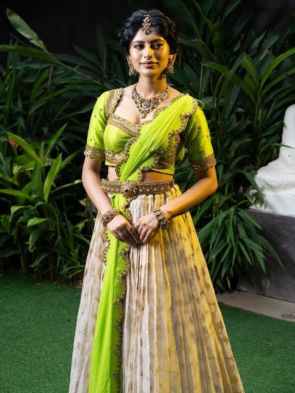 Wrapped in elegance, this half saree features a light gold tissue lehenga paired with a vibrant lime green princess katori blouse. The entire ensemble, including the dupatta, is finished with intricate handwork for a look of traditional grace.