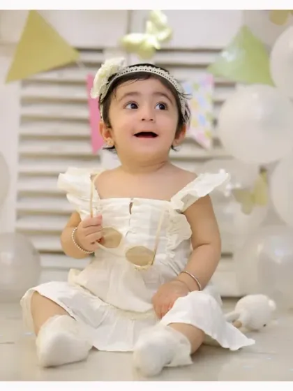 An elegant and simple first birthday theme with white balloons and delicate butterflies. This setup creates a dreamy and timeless portrait of your little one.