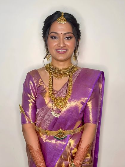 A bright, happy smile from a beautiful bride. The makeup is designed to enhance her joy, with a radiant finish and a lip color that complements her skin tone and saree.