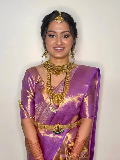 A bright, happy smile from a beautiful bride. The makeup is designed to enhance her joy, with a radiant finish and a lip color that complements her skin tone and saree.