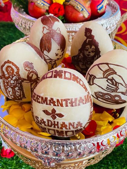 A beautiful set of custom-carved coconuts for Sadhana's Seemantham. The designs include traditional motifs like Krishna and a baby shower scene, making it a memorable keepsake.
