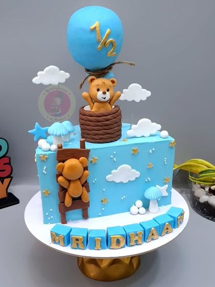 A detailed teddy bear themed half-birthday cake, complete with a hot air balloon and ladder.