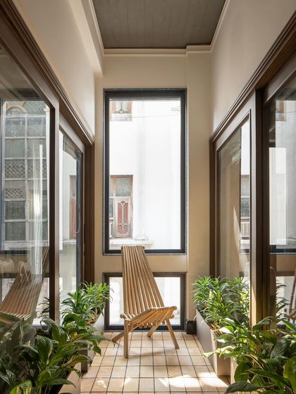 Light courts are designed as indoor gardens, breathing life into the home. This serene pocket of greenery, with its simple wooden chair, brings the outdoors in, balancing the facade's industrial strength.