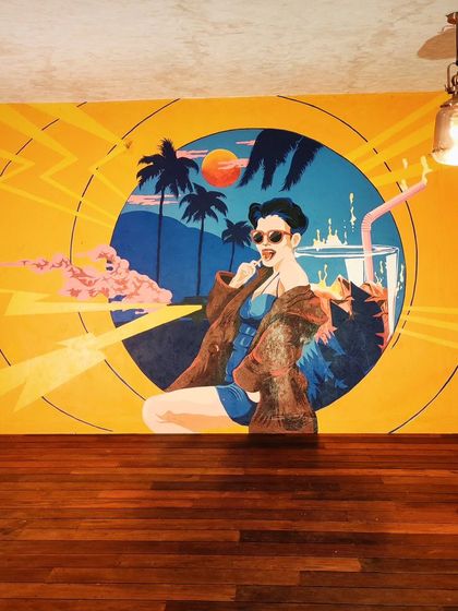 This pop-art mural of a woman chilling with a drink brings a cool, retro vibe to a terrace in Sarjapur. The bright yellows and blues make it a perfect, sunny backdrop for a party spot.
