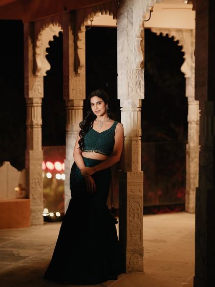 Posing against carved pillars, this shot highlights the mermaid silhouette of the lehenga and the intricate beadwork on the blouse.