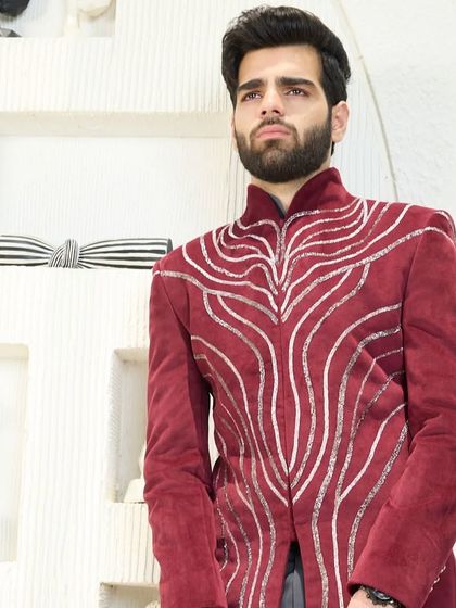 A close-up of the crimson velvet jacket, showcasing the fluid, silver embroidery that flows across the rich fabric. This is wearable art.