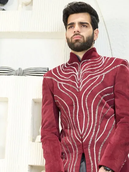 A close-up of the crimson velvet jacket, showcasing the fluid, silver embroidery that flows across the rich fabric. This is wearable art.