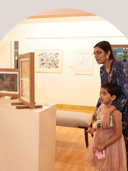 A mother and daughter look closely at a series of small sketches, sharing an educational moment.