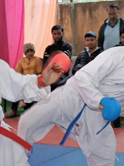 A close-up action shot from a sparring session. This shows a side kick being delivered with force, a key technique for maintaining distance and defending against an opponent.