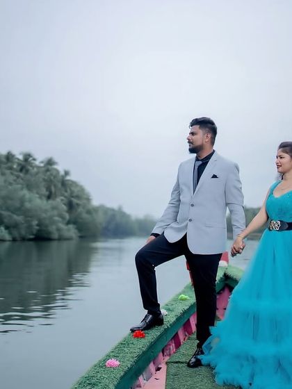 A cinematic pre-wedding shot on a boat, with the couple looking out at the horizon. The blue ruffled gown adds a touch of fairytale elegance.