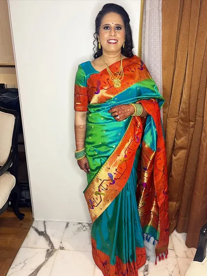 A full-length photo of Mrinal's reception look. The vibrant colors of her saree are balanced with glowing makeup and a bright smile.
