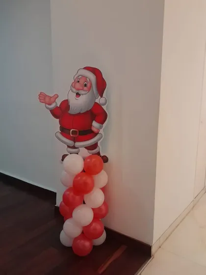 A cheerful Santa Claus cutout on a red and white balloon pillar. This prop was used as part of a carnival-themed birthday that had a festive touch.