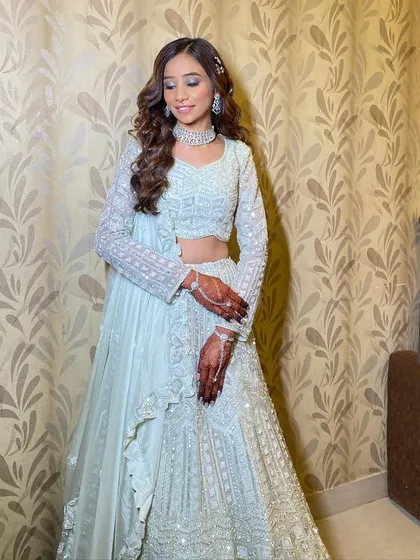 The complete look is all about soft elegance. The makeup is kept neutral to let the beautiful outfit and the bride's natural beauty shine.
