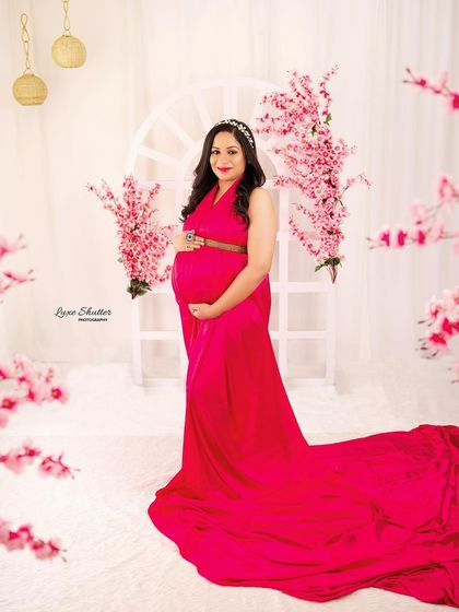 A frontal view of the mom-to-be in her pink gown, looking radiant and happy amidst the floral setup.
