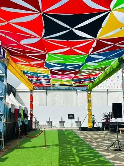 A covered walkway at the Ola event, featuring a vibrant, multi-colored canopy and artificial grass flooring. I use these elements to create visually appealing and functional pathways.