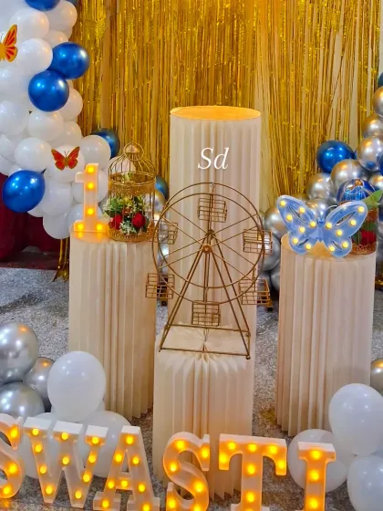 A detailed shot focusing on the props for the butterfly party, including the light-up butterfly, birdcage, and Ferris wheel on the plinths.