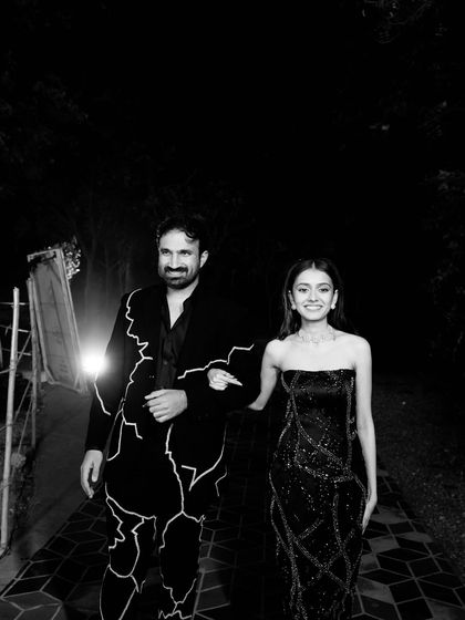 An Electrifying Cocktail Look: This couple broke the rules, with the groom's bold jacket setting the tone for the bride's chic, custom-embroidered black tube dress.