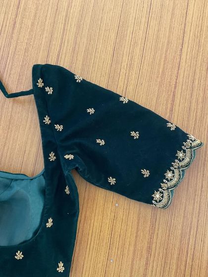 The sleeve detail of a simple yet elegant bottle green velvet blouse with minimal gold embroidery, worn by our client Rakshitha.