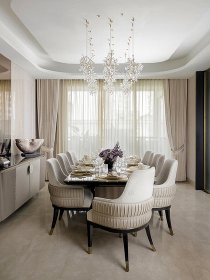 A gathering in grace. We designed this dining space for shared meals and stolen moments, under a canopy of crystal blooms. The neutral palette of the chairs and walls creates a calm, elegant atmosphere.