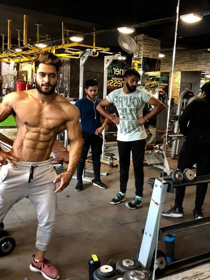 Surrounded by the tools of the trade. This is where transformations happen. A candid shot in the gym showing a stage-ready physique.