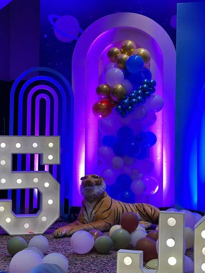 A detail shot from the party, showing a tiger prop next to the light-up number "5" and modern arch backdrops.