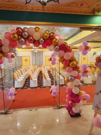 The entrance to the butterfly-themed party, featuring a grand balloon arch in pink, rose gold, and red that welcomes guests into the celebration.