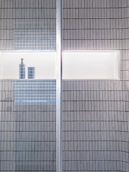 A detail of the shower in the son's bathroom in Apartment 56. The curved walls are clad in vertical mosaic tiles, and a backlit niche provides soft, ambient lighting, showcasing our attention to detail even in compact spaces.