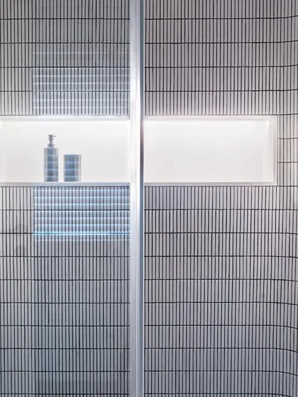 A detail of the shower in the son's bathroom in Apartment 56. The curved walls are clad in vertical mosaic tiles, and a backlit niche provides soft, ambient lighting, showcasing our attention to detail even in compact spaces.