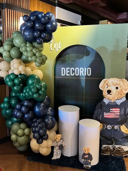 The main decoration for the Polo Ralph Lauren teddy bear theme. It includes a balloon arrangement in sophisticated greens and blues, and a large teddy bear cutout dressed in classic American style.