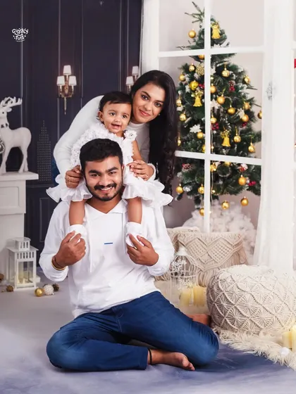 A happy family portrait, with the little girl sitting on her father's shoulders, all sharing a beautiful moment.