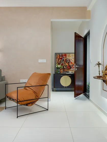 In this mock-up unit, I blended modern and rustic elements. The living area features a comfortable grey sofa and a leather lounge chair, while a custom-designed pooja niche with an arched form and backlighting adds a spiritual and sculptural element to the space.