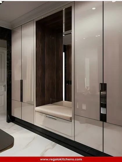 This wardrobe includes a clever built-in bench seat, creating a cozy nook for putting on shoes. The high-gloss finish and dark wood accents provide a modern, high-contrast look.