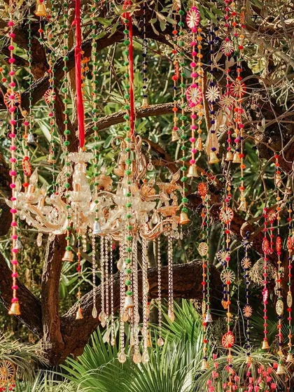 I love using natural elements in my decor. Here, I've hung elegant chandeliers and colourful tassels from the branches of a tree, creating a magical, bohemian-chic vibe for an outdoor Mehendi.