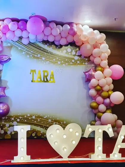 For a modern and glamorous naming ceremony, I use elements like balloon arches and large marquee lights. This "I love TARA" sign adds a fun, personalized touch and creates a fantastic photo backdrop.