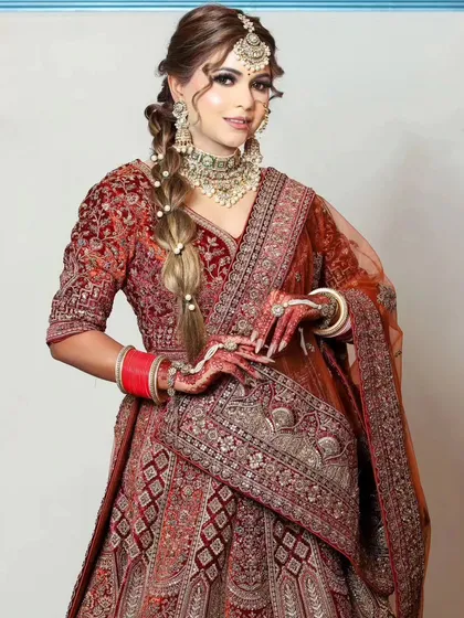 A full shot of a bride in a gorgeous rust-colored velvet lehenga, showcasing her complete look with braided hair.