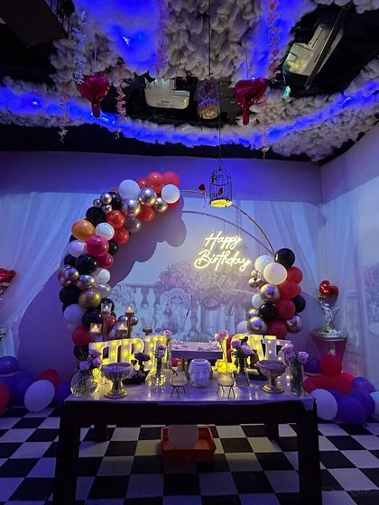 A stunning birthday setup in our 'Smoky Lounge' in Adyar, featuring a checkered floor, cloud-like ceiling decor, and a beautiful balloon arch.