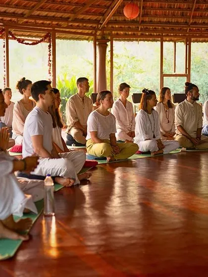 Students sit in quiet reverence during a Puja ceremony. This ritual, filled with mantras and offerings, purifies the space and sets a sacred intention for our time together.