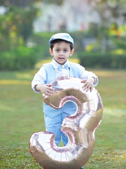 Dressed up and ready to celebrate turning three. This dapper young man looks so handsome in his suit, holding a giant balloon to mark his special birthday.
