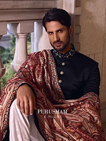 A moment of quiet contemplation. The rich fabric and intricate pattern of the shawl speak of heritage and a contemporary touch, perfect for a groom on his wedding day or for a formal evening.
