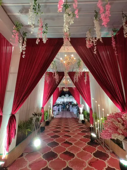 Another perspective of the red draped entrance, showing how the layers of fabric and hanging flowers create depth and a sense of procession for guests as they walk towards the main event area.
