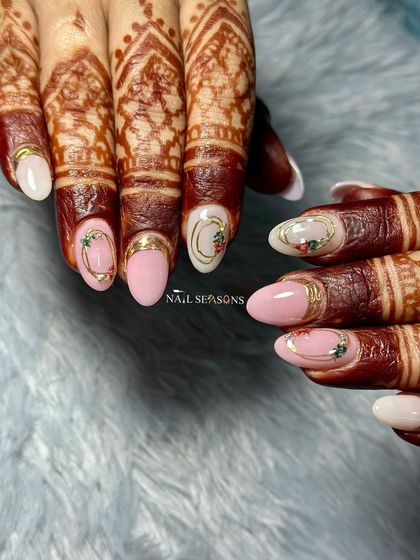 Minimal yet royal. These bridal nails feature a mix of soft pink and white, with delicate floral details and gold accents that look beautiful with her henna.