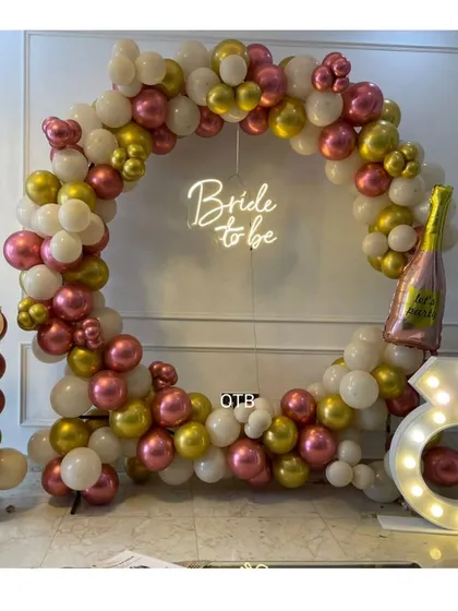 Let the bachelorette party begin! This circular balloon arch in white, gold, and pink, complete with a "Bride to be" neon sign and a light-up diamond ring prop, is perfect for those fun-filled photo sessions.