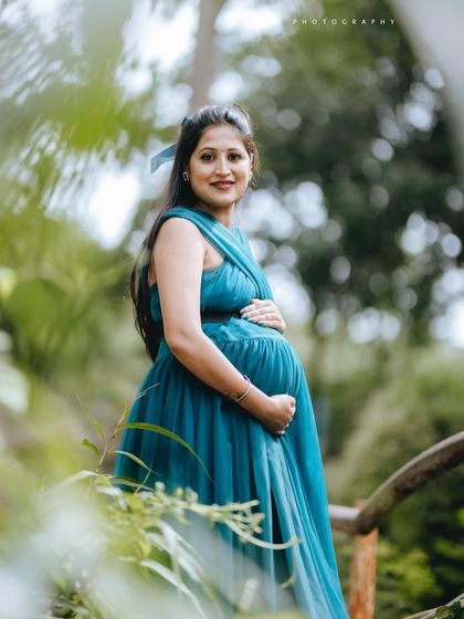 The rich teal color of this maternity gown looks stunning in natural light. Its simple, elegant design with a wraparound top is perfect for highlighting the baby bump in a comfortable and stylish way.